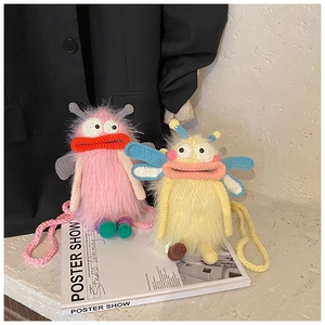 Détail des sacs bandoulière monstre en tricot rose et jaune sur un livre d'art blanc