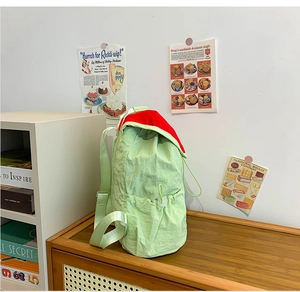 Detail of light green and red contrast school backpack on a wooden shelf in a bright room
