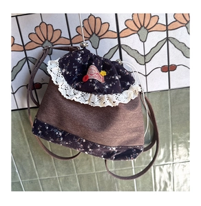 Detail of vintage drawstring backpack with lace trim and floral patterns on brown fabric