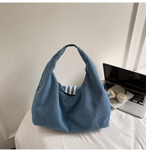 Detailed view of denim tote bag with triple white stripes on office desk setup