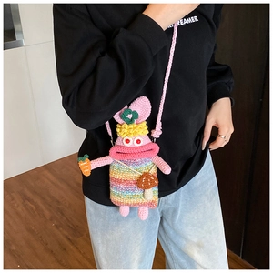 Detail of a handmade pink crochet crossbody bag with colorful stripes and cute charms