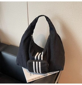 Close-up of black denim hobo bag with white stripes and matching mini coin purse detail