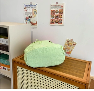 Detail of light green quilted drawstring bag with embroidery on a vintage wooden shelf