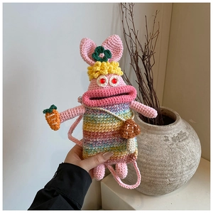Detail of handmade knit rabbit bag with rainbow stripes and decorative charms