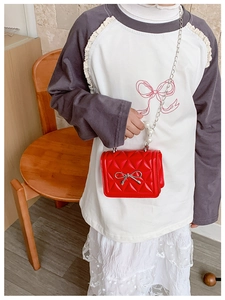 Détail du sac enfant matelassé rouge avec poignée en perles et nœud argenté