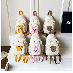 Détail de sacs enfant en toile avec broderies animaux sur présentoir minimaliste