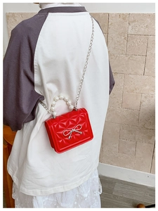 Détail du mini sac matelassé rouge avec poignée en perles et nœud métallique argenté