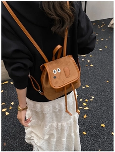 Détail d'un mini sac à dos en faux daim marron avec des yeux de dessin animé mignons
