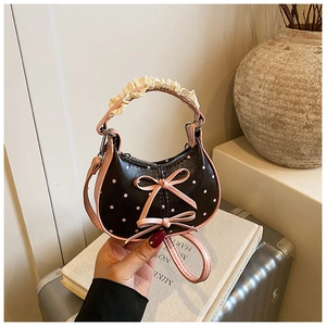 Detailed shot of mini pink polka dot bag with bow accents and ruffled handle grip