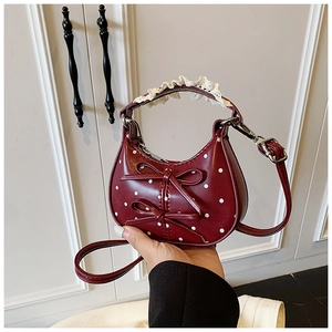 Close-up of burgundy polka dot handbag with white bows and lace trim details