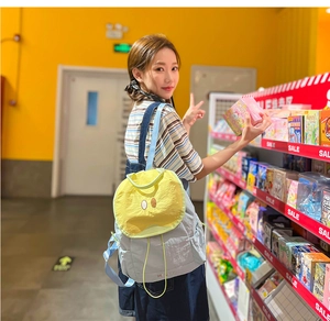 Detail of cute light blue nylon backpack with round yellow pocket and eyes embroidery