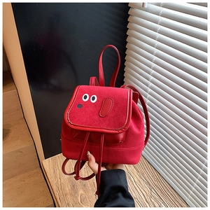Détail d'un petit sac à dos rouge pour enfant en daim avec un design de chien minimaliste