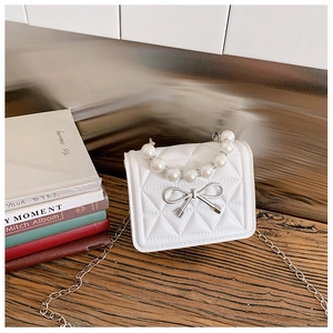 Détail du mini sac blanc matelassé avec nœud argenté et poignée élégante en perles
