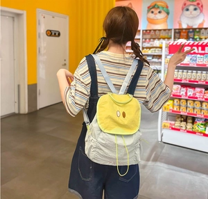Detail of cute yellow flap backpack with cartoon eyes and neon green drawstrings