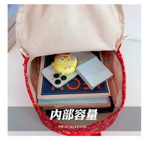 Detail showing high-capacity interior of red cartoon schoolbag with books and accessories