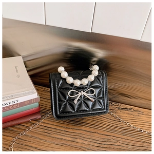 Détail du sac enfant matelassé noir avec poignée en perles et décoration de noeud