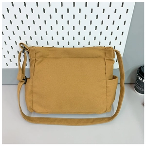 Detail view of the mustard yellow canvas tote bag with side pockets and adjustable strap