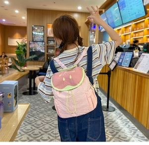 Detail of pink watermelon backpack featuring green lid, seed embroidery and HELLO text