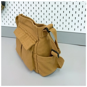 Detail of ginger yellow canvas tote bag featuring multi-pocket utility design and buckle strap