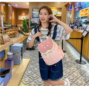 Detailed view of kids cute pink watermelon backpack with Hello text in a cafe setting