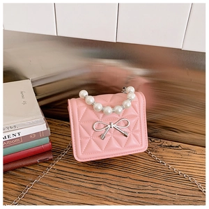 Détail d'un mini sac rose matelassé avec poignée en perles et nœud métallique