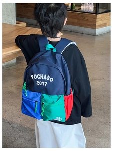 Detail view of a navy blue school backpack with colorful contrast panels and letter print