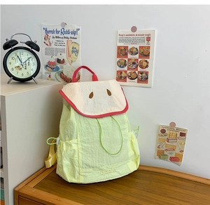 Detail of yellow nylon kids backpack with apple embroidery and cream drawstring closure