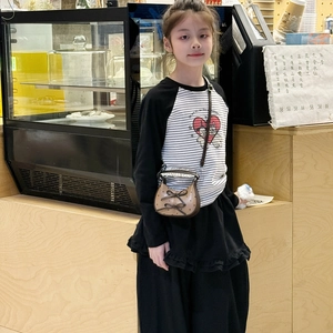 Children's khaki polka dot bow handbag with striped outfit in a cafe setting