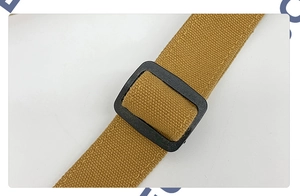Close-up of adjustable woven canvas strap with durable plastic buckle on mustard yellow bag