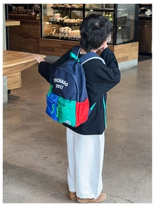 Detail view of colorful patchwork school backpack featuring bold letters and side pockets
