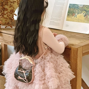 Girl carrying a cute polka dot mini handbag with a pink bow and adjustable strap