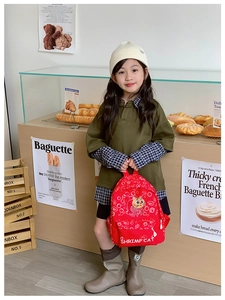 Detail of red cartoon kids backpack with cute cat print in a cozy bakery setting