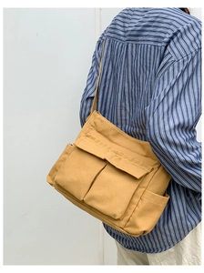 Detail of mustard yellow canvas tote bag with front flap pockets and adjustable strap