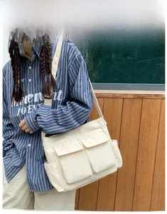 Detail of a large off-white canvas tote bag featuring two front flap pockets and side pouches