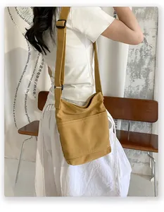 Detail of mustard yellow canvas crossbody bag with adjustable strap and front pocket