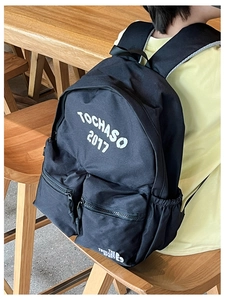 Detail of black canvas backpack showing large capacity main bag and dual zip front pockets