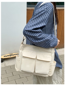 Outdoor shot of beige canvas tote bag with multiple flap pockets and adjustable strap