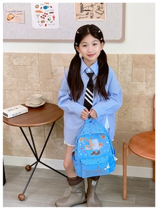 Close-up of blue school backpack featuring camel cartoon print on a child model