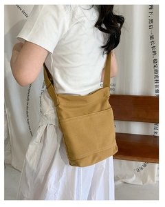 Detail of yellow canvas crossbody bag with two front pockets and white contrast stitching