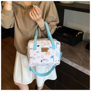 Detail of colorful giraffe and rainbow prints on a white crossbody diaper bag