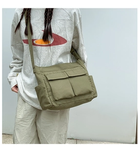 Detail of army green canvas tote bag with large front pockets and utility style