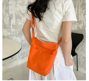 Orange canvas crossbody bag back view showing size and scale on a model during daily use
