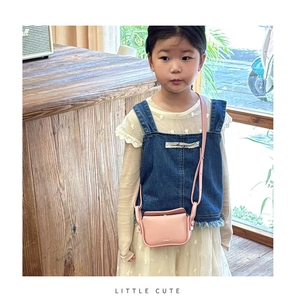 Pink leather crossbody bag for kids shown in a stylish cafe setting with soft lighting