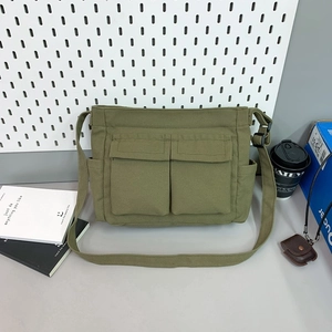 Close-up of olive green canvas tote bag with front flap pockets and adjustable strap