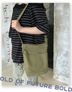Detailed side view of an army green canvas crossbody bag featuring functional outer pockets