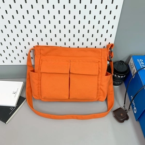 Detail of orange canvas messenger bag with double flap pockets and adjustable strap