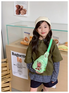 Mädchen mit hellgrüner Segeltuch-Brusttasche mit Cartoon-Print in einem gemütlichen Café