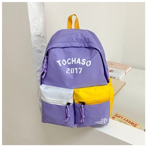 Detail of purple canvas backpack showing color-block pockets and top yellow handle