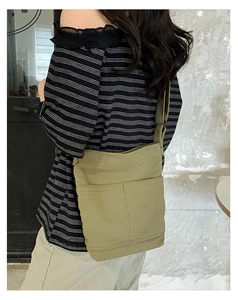 Olive green washed canvas shoulder bag with multiple pockets worn by a model in casual style