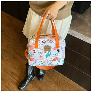 Detailed view of white canvas tote featuring colorful dinosaur prints and orange handles